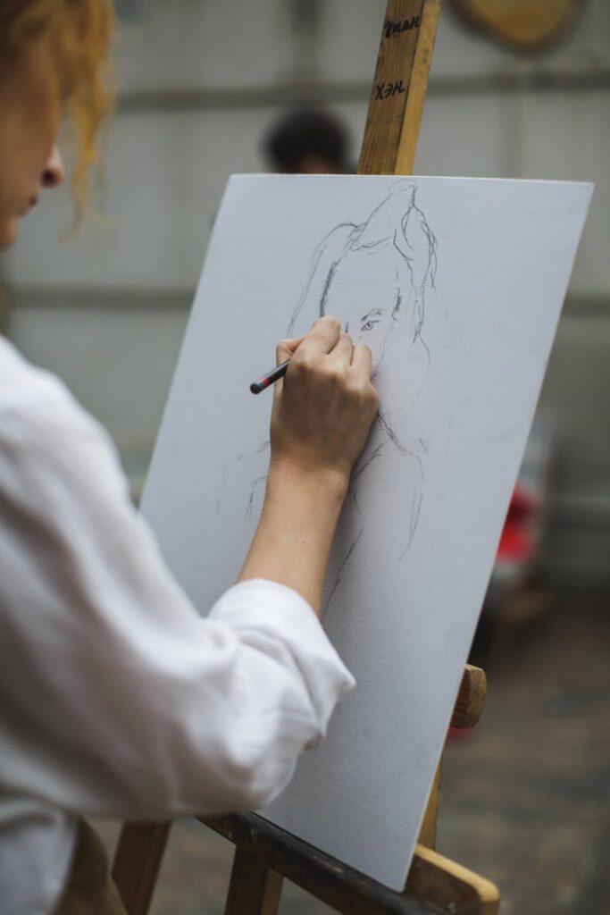 Woman in White Long Sleeve Shirt Drawing on Paper